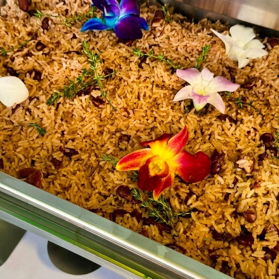 Rice and beans in a buffet tray, garnished with colorful orchids and fresh herbs.